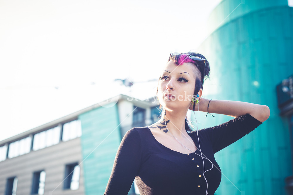 Young stylish girl enjoying music in urban setting