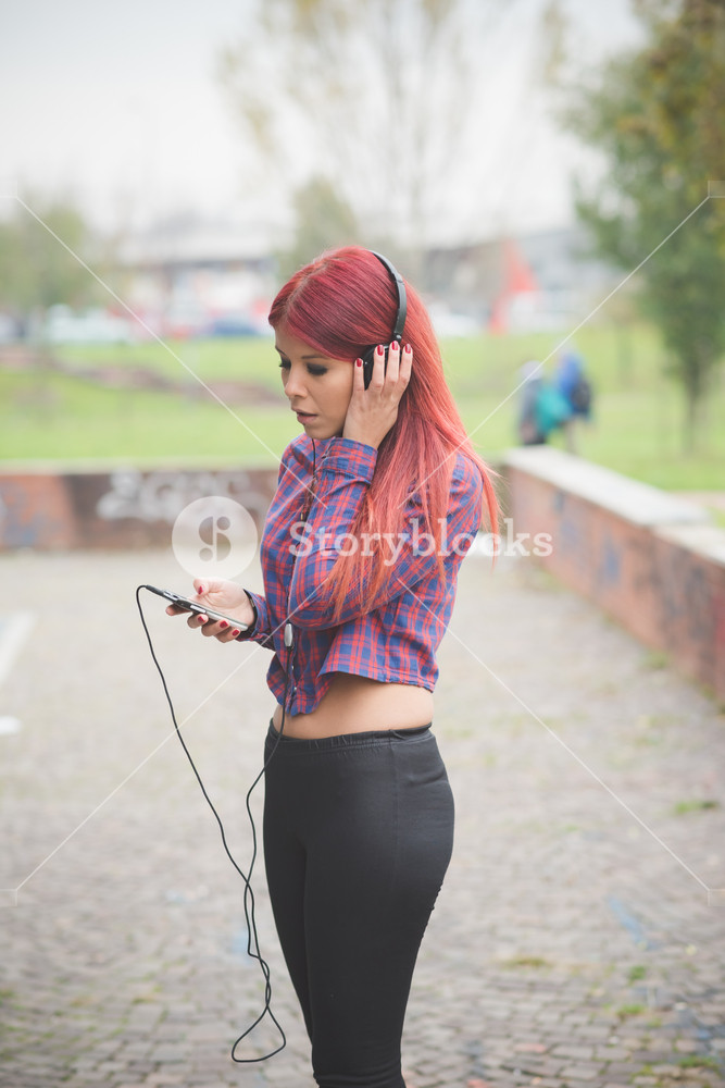 Vibrant redhead enjoying Milan's city life, listening to music outdoors