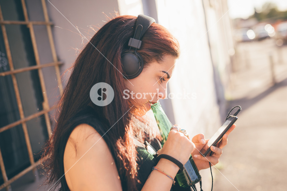 Young woman enjoying music while walking through the street - relaxation, music, technology concept - wearing black shirt, focused on screen