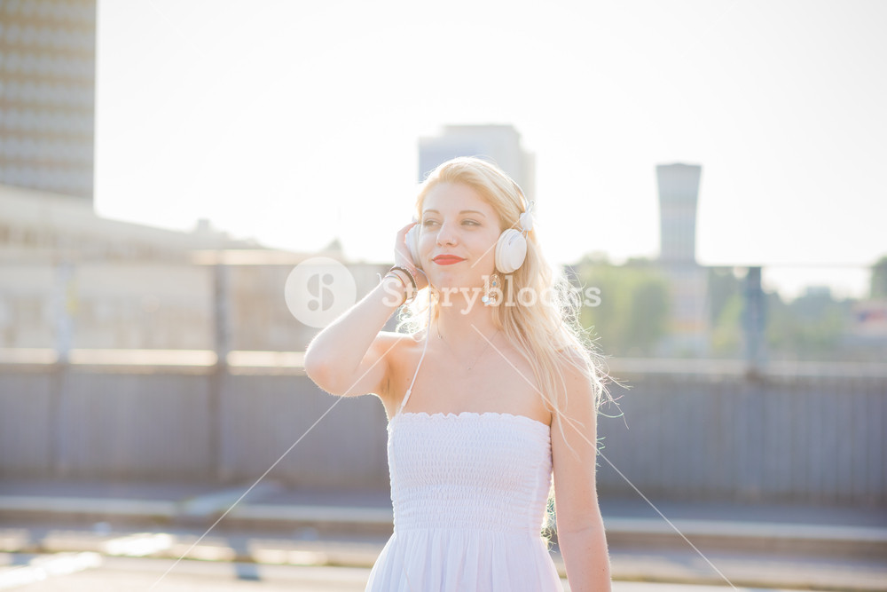 Young woman in the city, backlit, enjoying music - relaxing, music concept