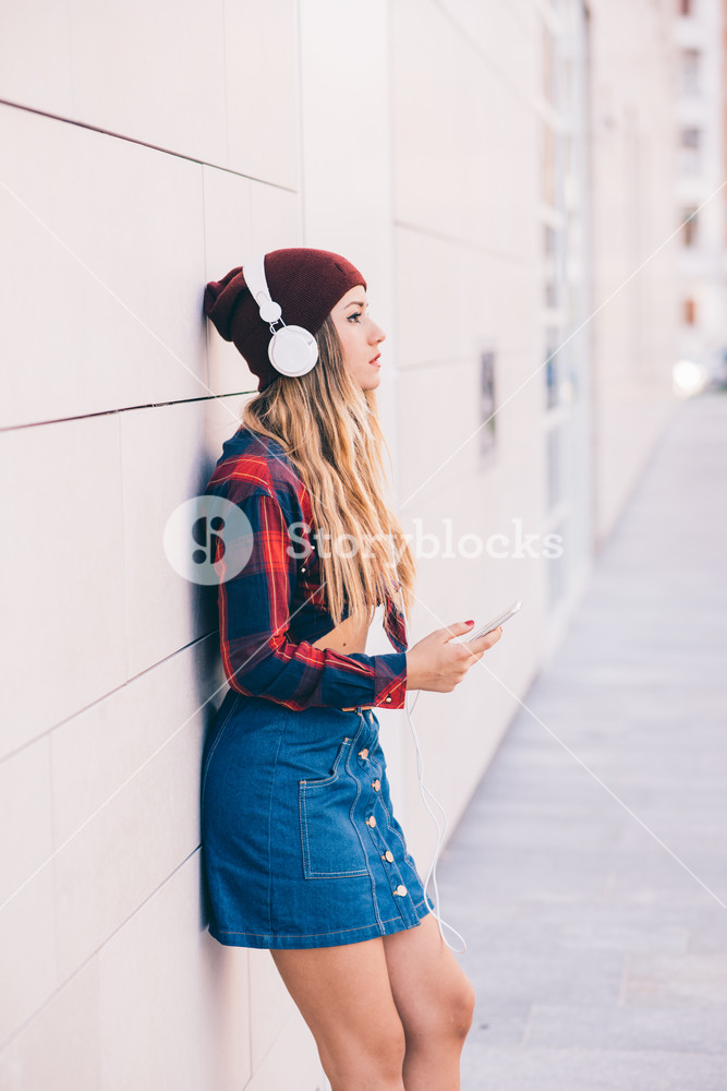Blonde woman enjoying music outdoors with smartphone - city, relaxation, technology