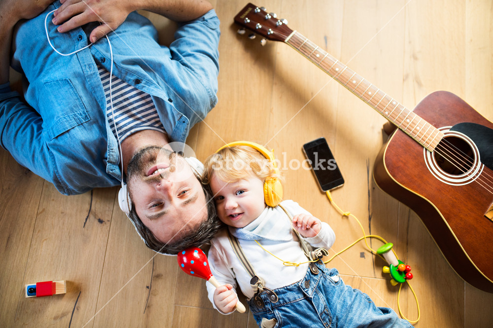 Father and son enjoying music at home with technology and instruments