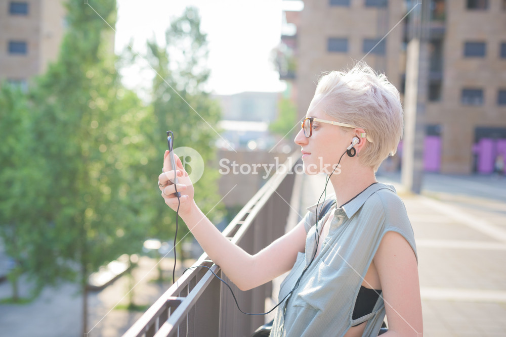 Young designer listening to music with smartphone and earphones - technology, social network, relaxing concept