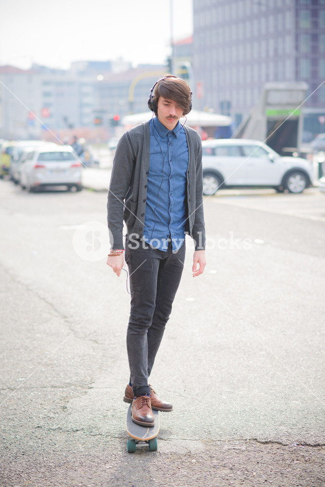 Young man skating through the streets with headphones - sportive, music, relaxing concept