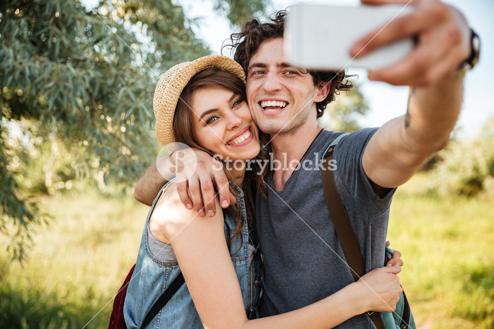 Smiling couple hiking in the forest and taking a selfie Royalty-Free ...