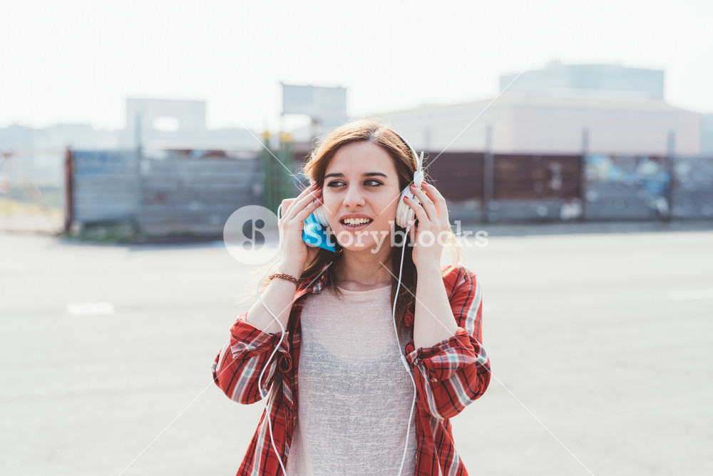 Woman enjoying music outdoors with headphones and smartphone - music, relaxation, technology concept