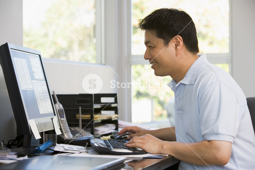 Man in home office using computer and smiling Royalty-Free Stock Photo ...