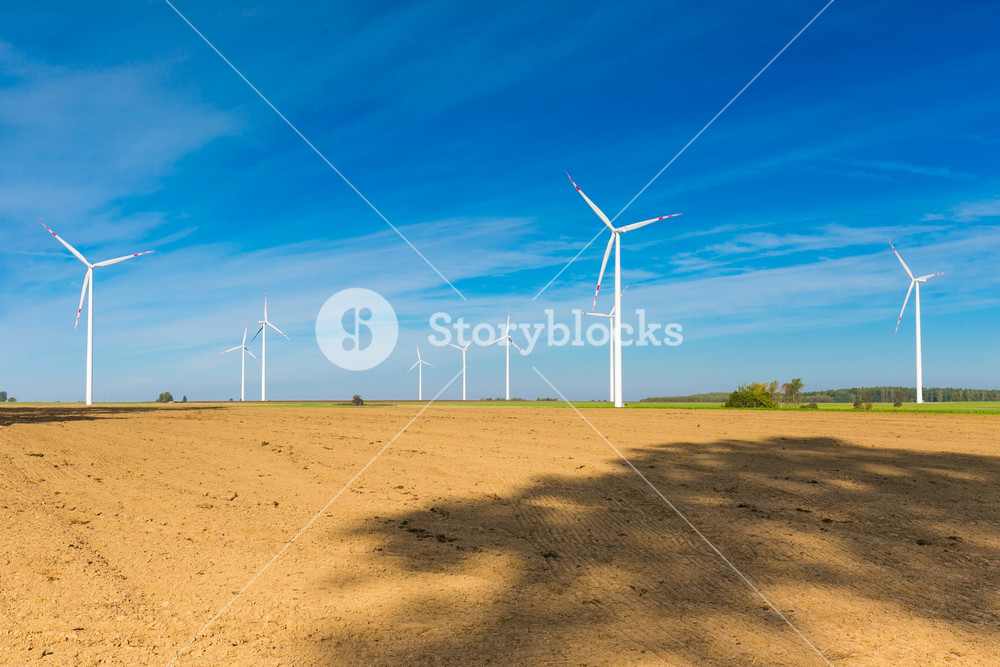 Fields and Wind Farm. Serene landscape with blue sky over plowed fields ...