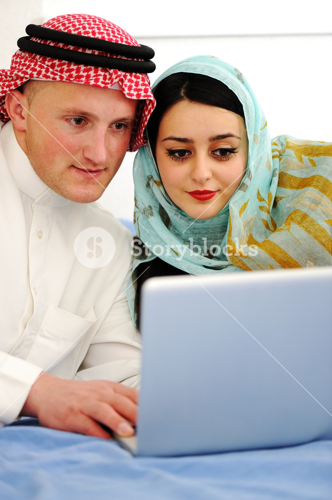 Portrait of a joyful couple sitting on a sofa using a laptop Royalty ...