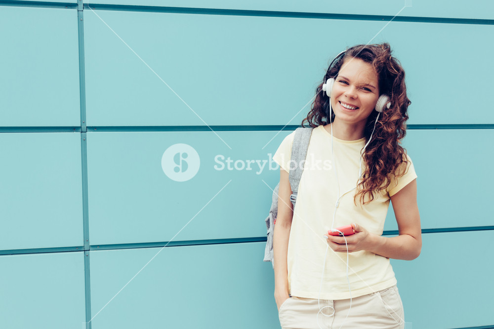 Smiling girl in a yellow T-shirt enjoying music with headphones