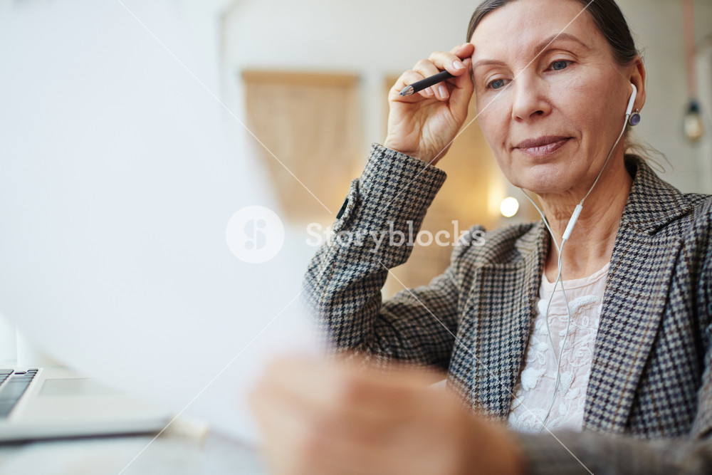 Businesswoman reading paper and listening to music