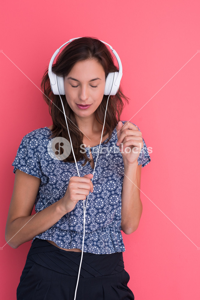 Joyful woman enjoying music with headphones on a red background