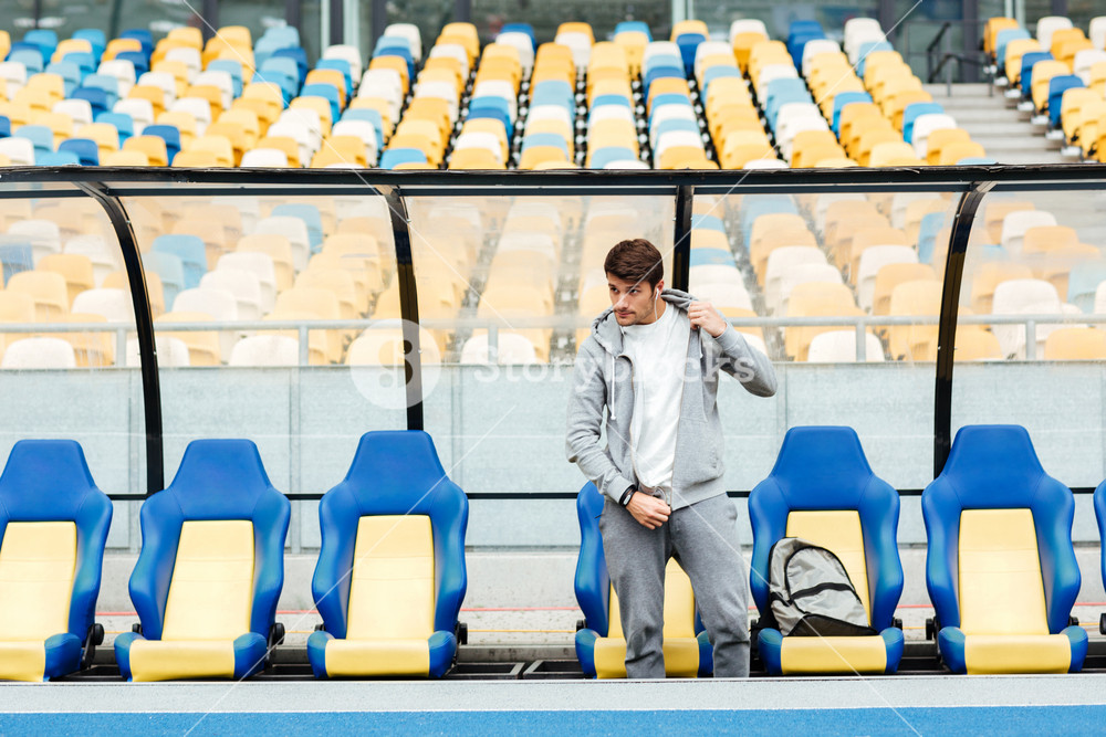 Focused athlete at the stadium, enjoying music and observing.