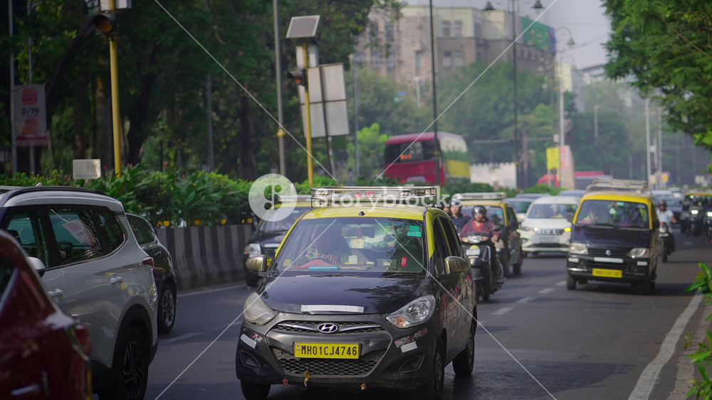 Mumbai, India - December 2 2025: A wide daylight shot of the moving city road traffic of cabs, cars, and bikes during office or rush hours in a commercial district in the Indian financial capital