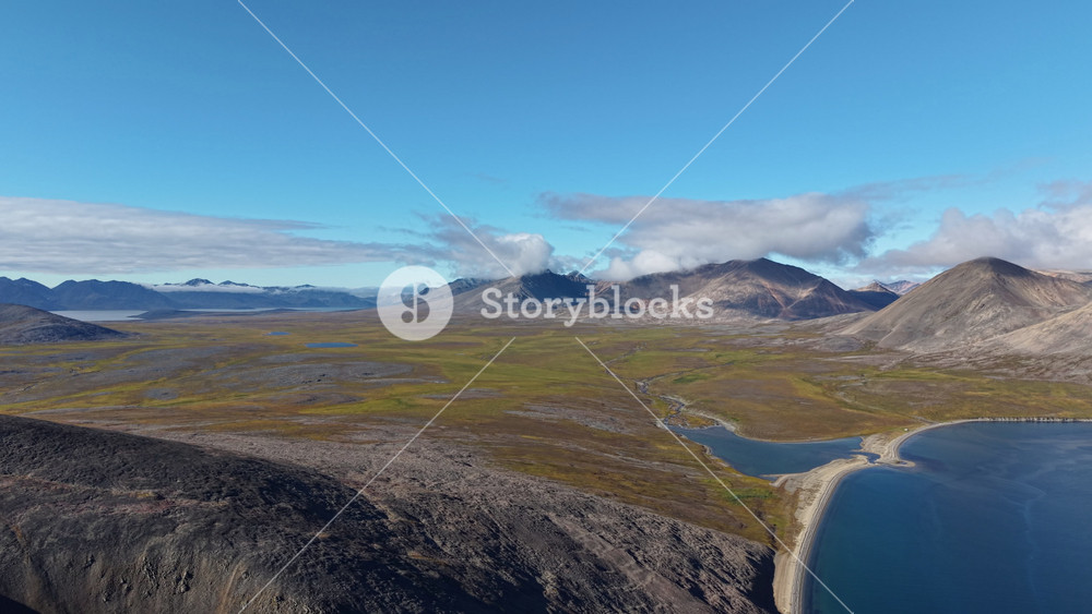 Aerial shot of Rumilet Bay Chukotka captures blue water, tundra and cone mountain. Smooth pan shifts the horizon and reveals new coastline
