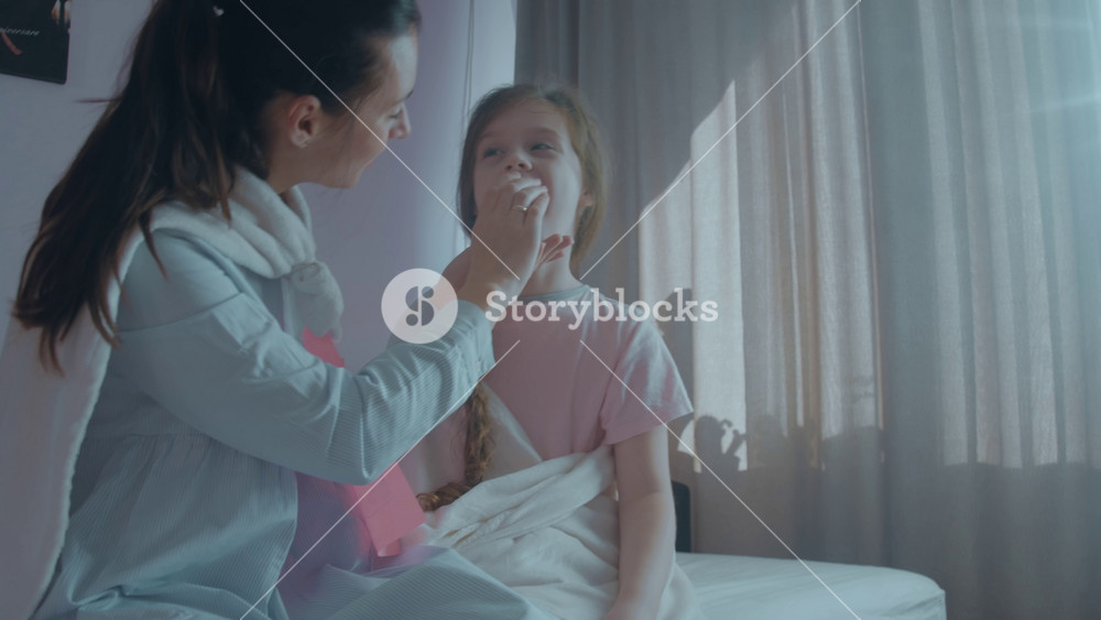 Loving mother with letter S on her chest and superhero cape is giving medicine to treat the soar throat of her child. Mom with super powers