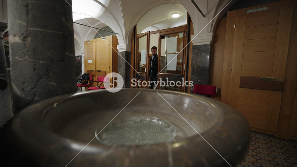 Believer entering a church, blessing himself with Holy Water and the Sign of the Cross, spiritual purification, and revering God's house.