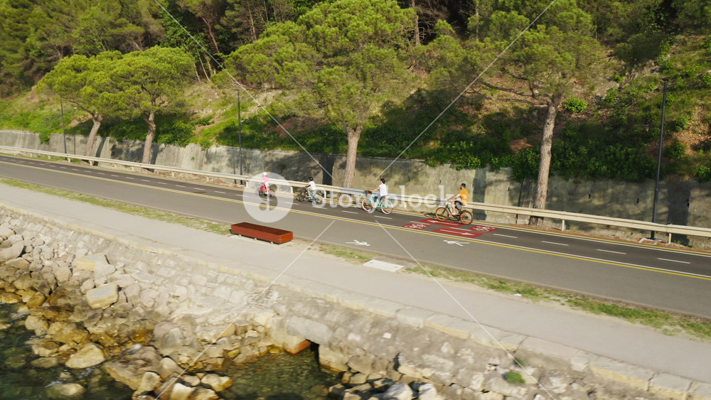 Family, two children, and parents cycling along a fantastic seaside route, aerial view. Traffic-free and family-friendly rides concept.