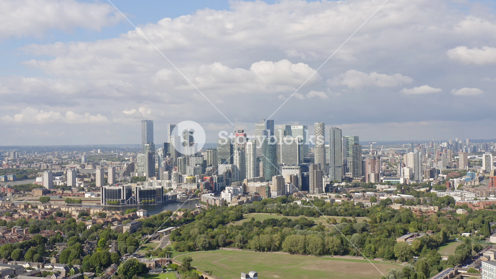 London, UK - September 11 2022 - Business district of London, skyscraper-packed peninsula Canary Wharf, with parks and river Thames nearby, aerial view.