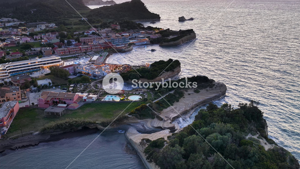 Canal D'Amour, Corfu, Greece: A mesmerizing aerial view of the iconic Canal D'Amour, revealing its unique rock formations and the vibrant coastal town at dusk.