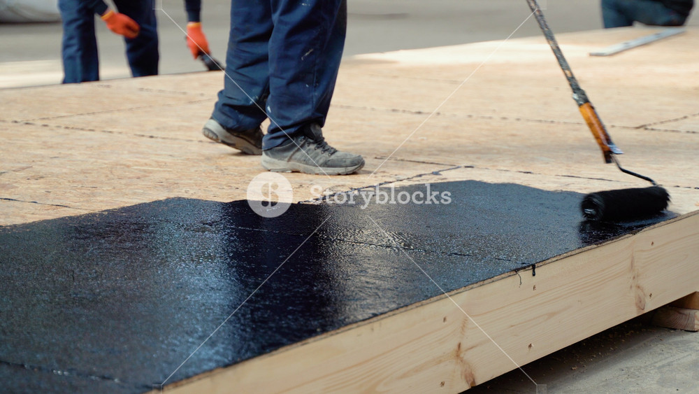 Applying hot resin to the floor for waterproofing, roller and bucket of resin, black and liquid resin. Modular prefabricated houses concept