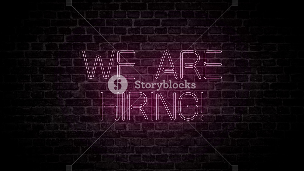 We are hiring neon sign in a brick wall. Concept of Search job,employment,vacancy,business and work. Led lights banner text with blue arrows and black background in 4k.