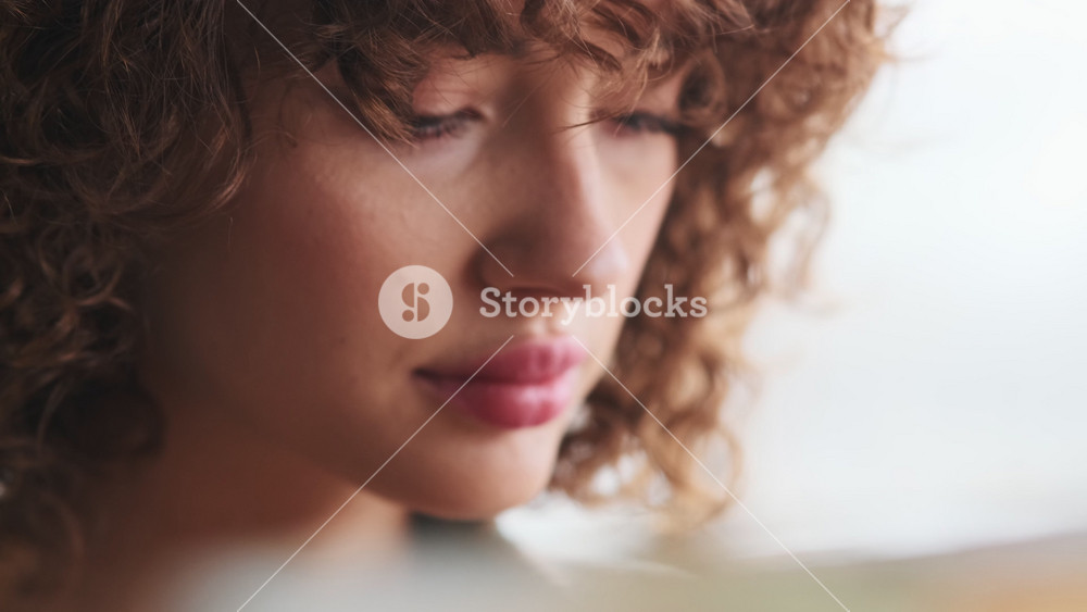 A close-up view of a pleased woman artist is standing next to the easel and painting something in her art studio