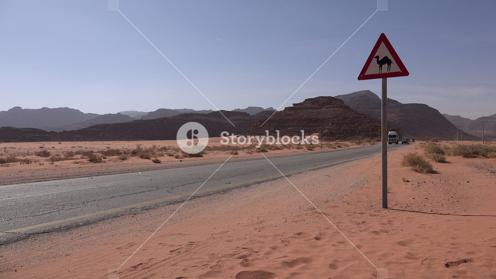 JORDAN NOVEMBER 2016: Traffic drives through the Jordanian desert, past a sign warning for camels, travel and transport in the Middle East