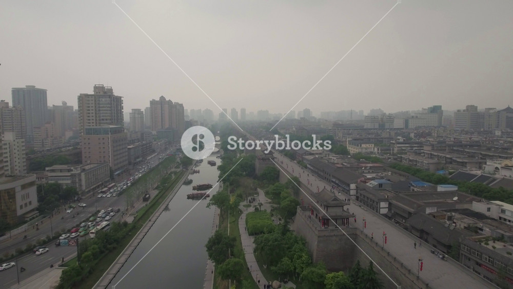 Aerial drone flight over the ancient city walls of Xi'an, former capital of China. The modern office towers on the left side contrast with the classic architecture inside the walls.