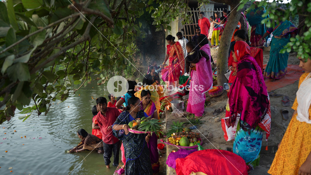 Bogura, Bangladesh - 20 December 2023: View of Hindu devotees performing religious rituals and offering prayers by the riverbank during a festival.