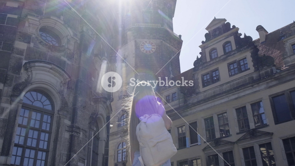 A female tourist with long flowing hair admires the stunning and beautiful architecture of Europe on a warm sunny day.