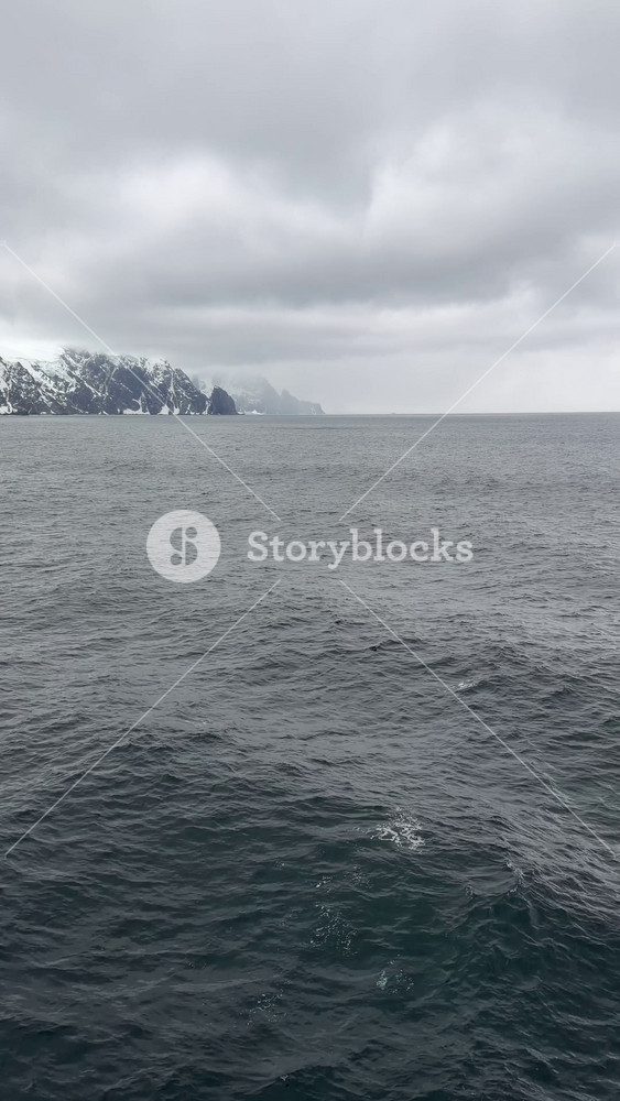 Antarctica Cruise Ship Walking Up to Handrail Point of View Tilt Up to Reveal Mountain Range and Ocean Moody Cloudy Sky Travel (Vertical Video)