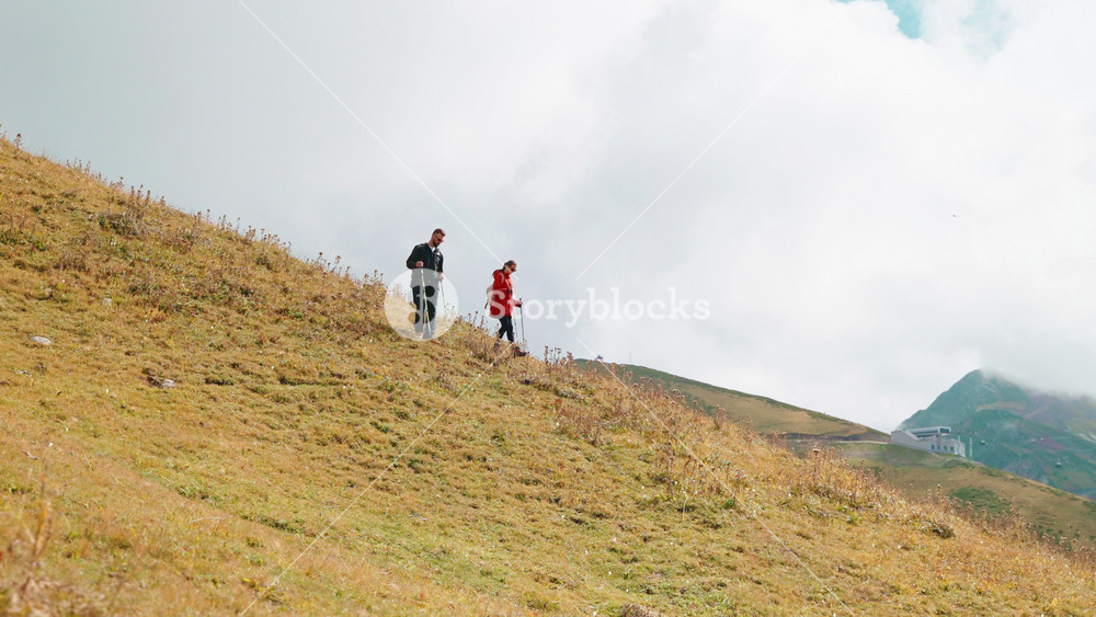 backpackers in mountains, man and woman walking together on slope of high mount and admiring landscapes, local tourism in ecological place