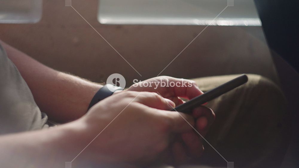 man using in public transport, closeup of hands swiping touchscreen, surfing internet and viewing news tape, of ferryboat on Tagus river to