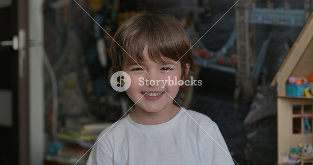 Close-up Portrait of Happy Little Child Bursting in Laugh. Kid Boy Laughs Indoors Closeup. Portrait of Little Boy Child Looking and Smiling to Camera. Face Funny Contemplative Kid. Slow Motion.