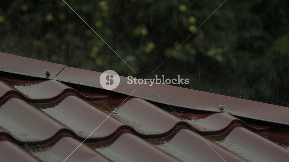 Heavy Rain Pouring Down on Red Metallic Roof of House. Gutter During Rainy Day. Slow Motion of Heavy Rain Falling on House Roof. Water Falling Down to Gutter From Roof During Heavy Rain Storm.