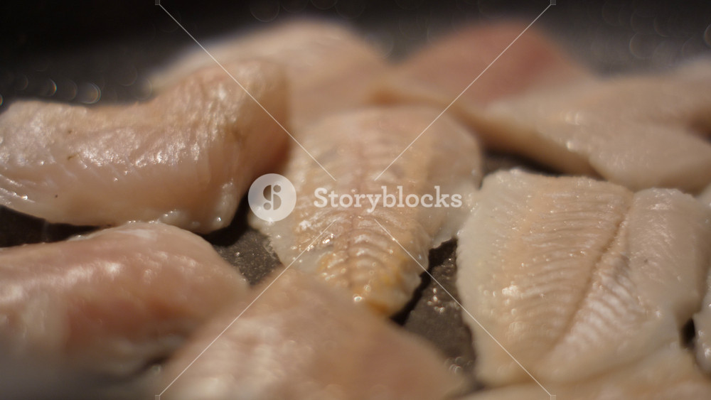 Close up Frying Fillet Hake Fish of Frying Pan With Oil. Roast Healthy Food. Fried Cod Fish Pieces Fillet With Spice Closeup. Healthy Diet Food Omega 3. Low-calorie white meat.