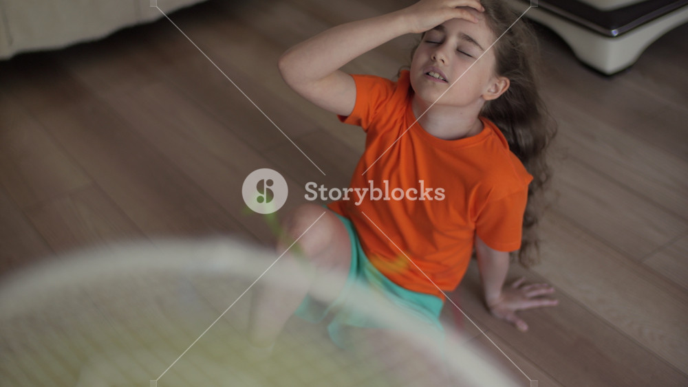 Children Suffering From Summer Heat Enjoy Fresh Cool Breeze Blowing Fan. Girl in Front Fan Hot Day on Home in Living Room. Child Enjoying Cool Wind From Electric Fan at Home at Summer Heat Weather.