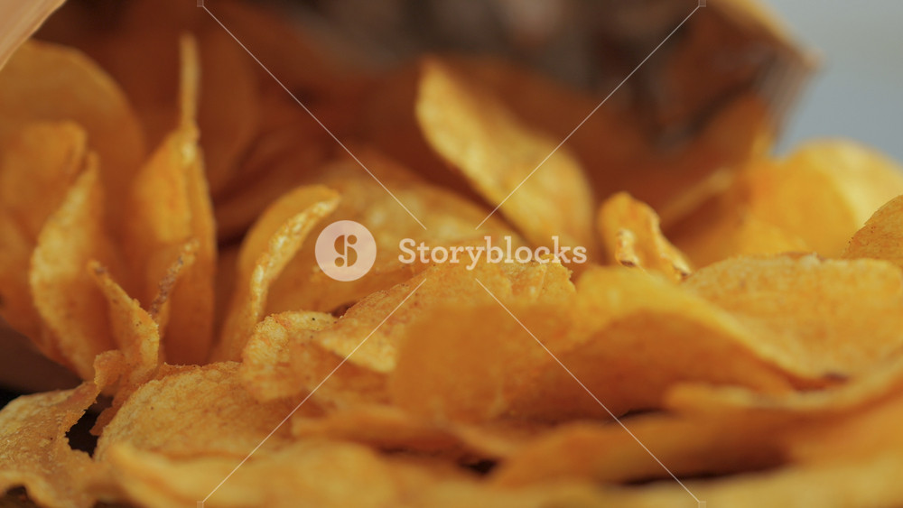 Close-up Potato Chips In Open Package. Potatoes Chips. Person Hands Take Potato Chips From Pack on Wood Table. Eating Fast Food, Junk Food at Home. Childhood Obesity. High Calorie Food.