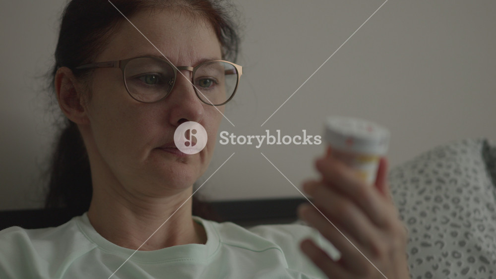 Female Checking Pills. Woman Sitting in Bedroom, Carefully Reading Instruction Leaflet While Holding Prescription Pill Bottle Before Taking Medications at Home. Medical Insurance Medicare.