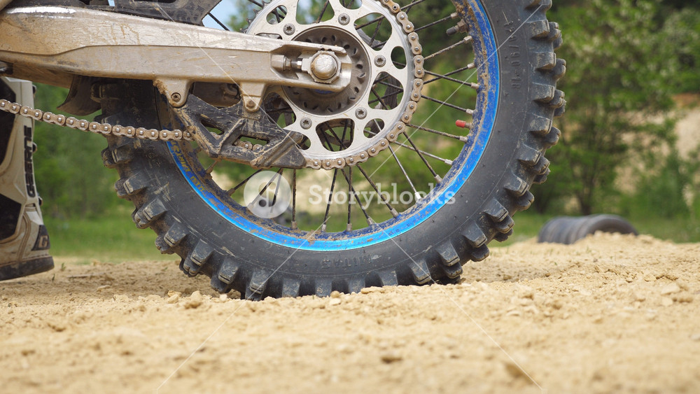 Close up wheel of powerful off-road motorcycle spinning and kicking up dry ground. Professional motocross rider starting race or training