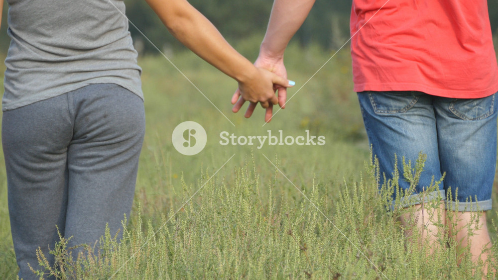 Young couple joining hands outdoor. Man and woman taking arms on nature background. Male and female hands comforting and stroking each other. Symbol of love and devotion. Romantic outside. Close up.
