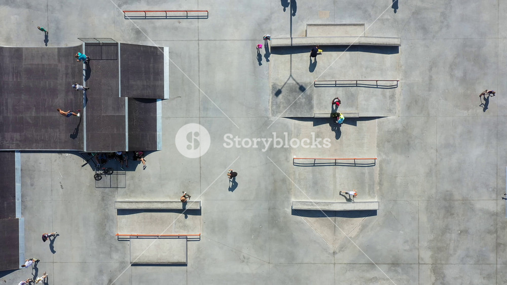 Teenagers riding on skateboards and scooters at urban park on summer day. Children practicing different tricks on equipments at modern skatepark. Concept of active healthy lifestyle. Aerial view