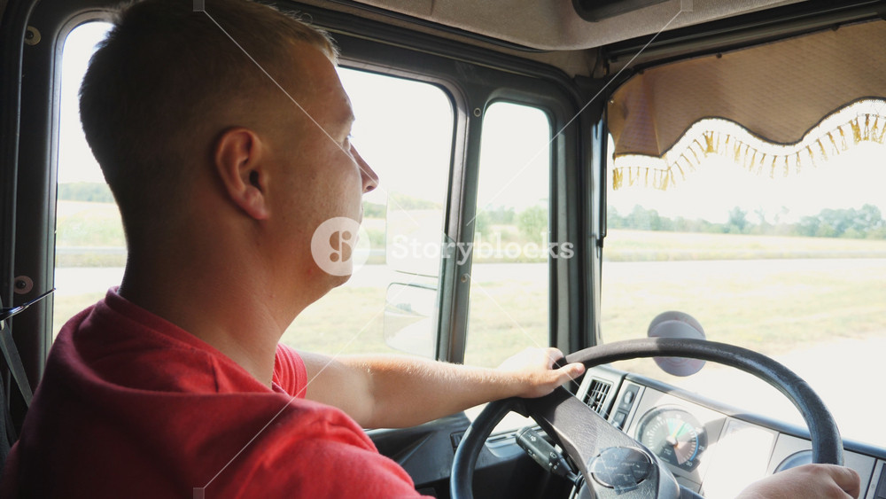 Close up of trucker speaks on walkie-talkie while driving car at sunny day. Lorry driver riding on country road and talking on radio communication. Logistics and transportation concept. Slow motion.