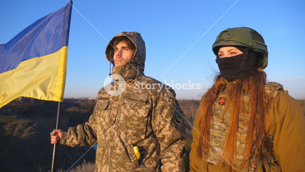 Soldiers of ukrainian army holding waving flag of Ukraine. Military people lifted up flag at the hill as victory against Russian aggression. Concept of invasion resistance and end of war. Slow motion.