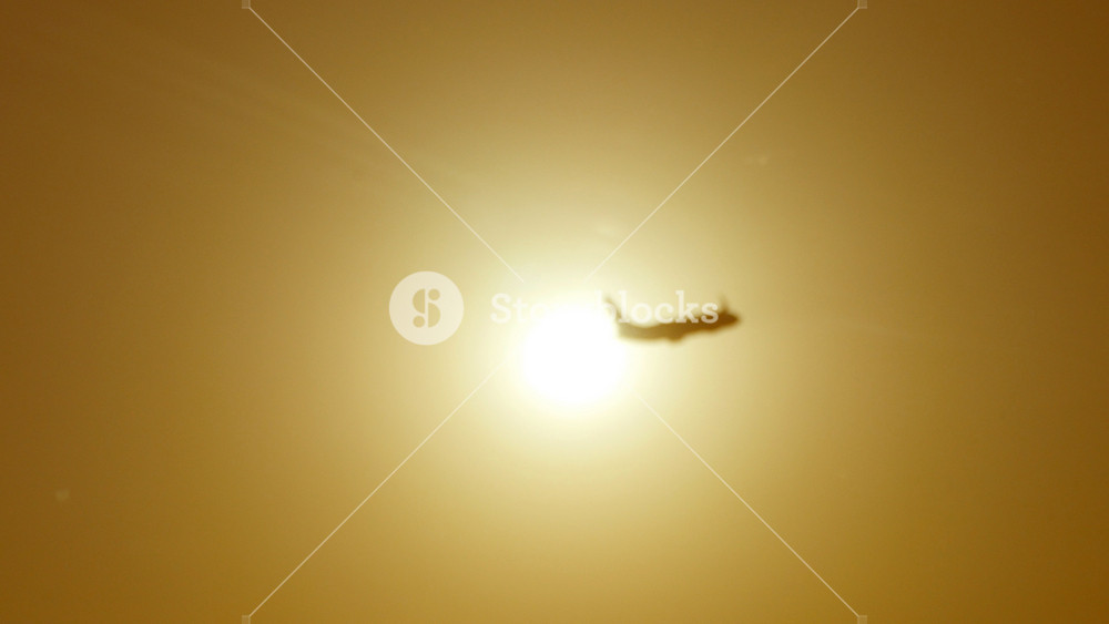 Silhouette of passenger airplane flies across sun at sunset. Plane taking off at sunrise background. Aircraft crossing sunrise at beautiful morning sky. Close up.