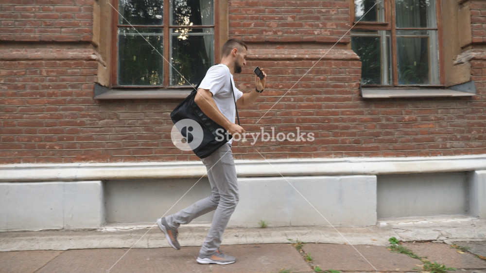 Successful businessman running along urban street and talking by phone. Young man with briefcase rushing to business center. Office employee commuting at work. Late to job or meeting. Career concept