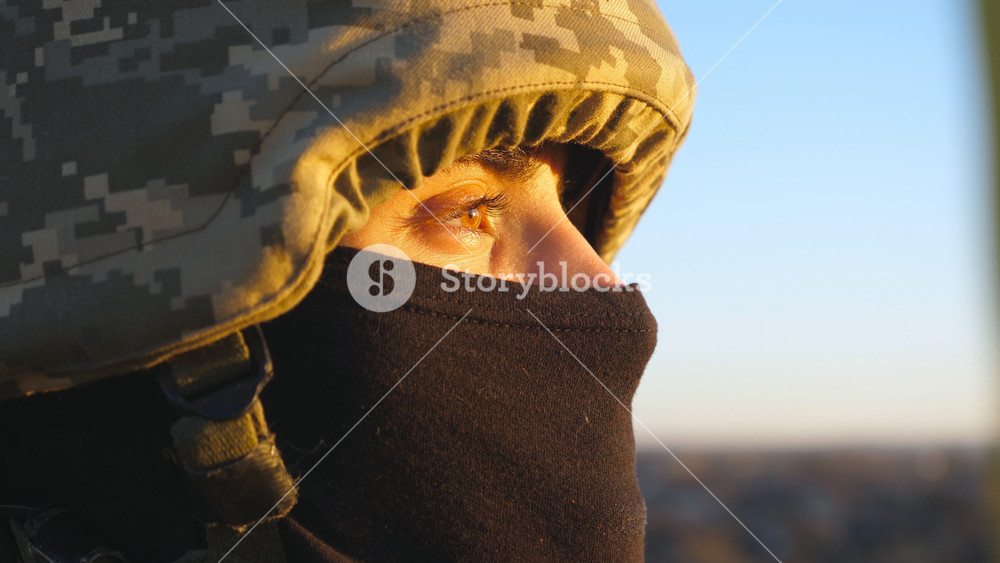 Gaze of male ukrainian army soldier in helmet and balaclava outdoor. Profile view of young military man looking with hope at sunset. Invasion resistance. War between Russia and Ukraine. Close up