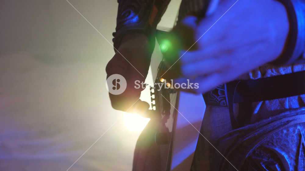 Arms of unrecognizable man playing on electric guitar at stage during rock concert. Hands of musician playing solo on guitar. Beautiful
