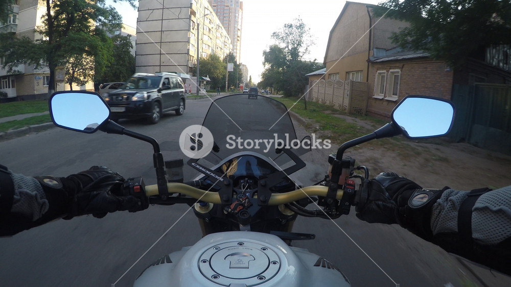 Point of view of a motorcycle rider rides in town road in high speed at sunset. The viewpoint of motorcyclist driving in the city streets. Pov Close up.